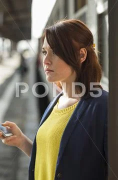 Young Woman With Cell Phone At Train Station