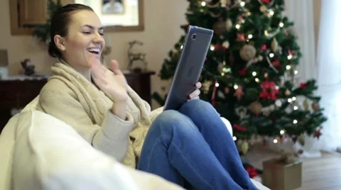 Young woman chatting on tablet computer, christmas tree in background Stock Footage 10742386
