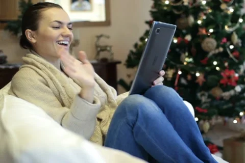 Young woman chatting on tablet computer, christmas tree in background Stock Footage 10742390
