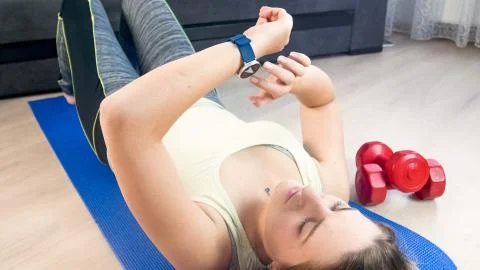 Young woman checking her parameter on fitness smart watch after exercising on Stock Photos