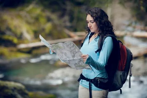 Young woman checking map by stream Stock Photos