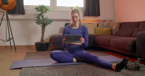 Young woman checking tablet for next workout and stretching exercise Stock Footage