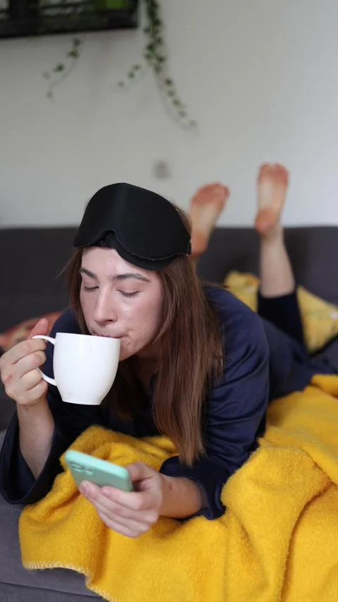 Young woman checks messages while enjoying morning coffee in bed Video stock 340086969