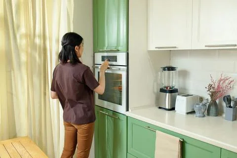 A young woman chooses a baking program that is ergonomically integrated at chest Stock Photos