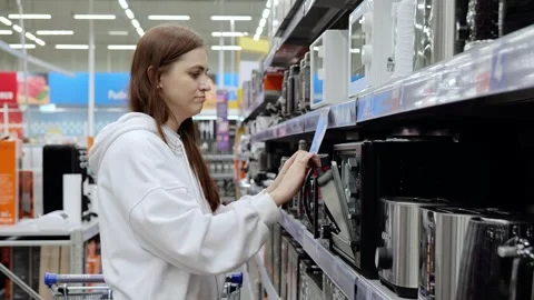 Young woman choosing new microwave oven in a home appliance store. Electronics Stock Footage 341289341