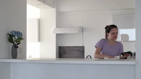 A young woman is cleaning kitchen surface and interrupts by phone notification Stock Footage 168754057