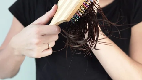 A young woman is combing the ends of her hair Stock Footage 98493652