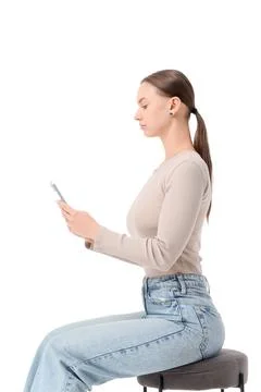 Young woman with correct posture using mobile phone on stool against white ba Stock Photos