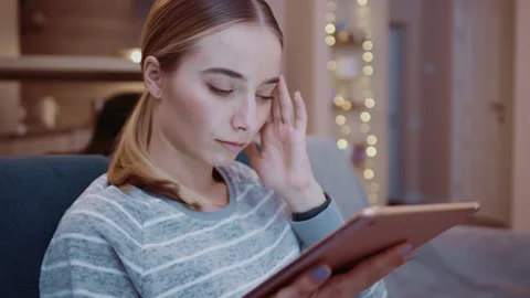 Young woman on couch using tablet to shop online at home feel sick unhappy Stock Footage 151339782