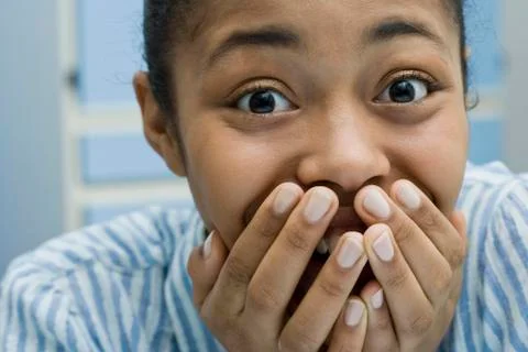 A young woman covering her mouth and laughing Stock Photos