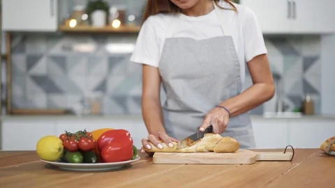 Young woman cutting bread with sharp knife Stock Footage 100031292