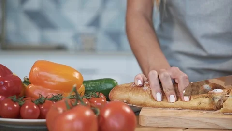 Young woman cutting bread on table Stock Footage 100031203