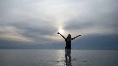 Young woman dances at sunset on the sea coast Stock Footage