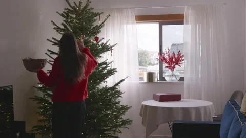 Young woman dancing and decorating Christmas tree in cozy bright living room, 4K Stock Footage 324924115