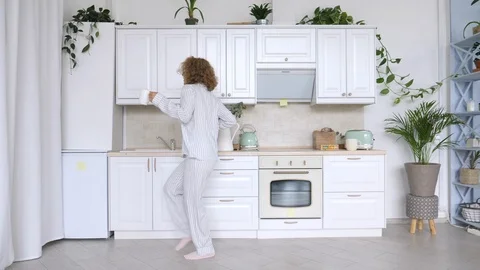 Young Woman Dancing And Using Cellphone In Kitchen. Stock Footage 94877611