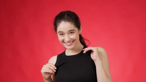Young woman dancing energetically and coquettishly against red background Stock Footage 248123700