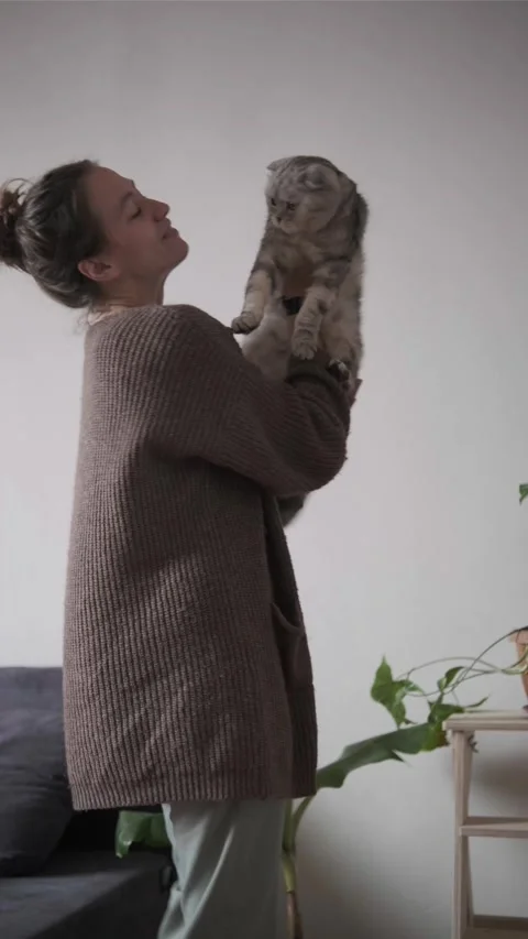 Young woman dancing at home while holding her cat in her arms Stock Footage 336555638