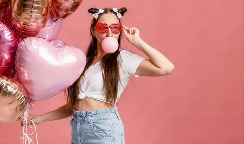 Young woman dancing, smiling and having fun with bubble gum near big branch o Stock Photos