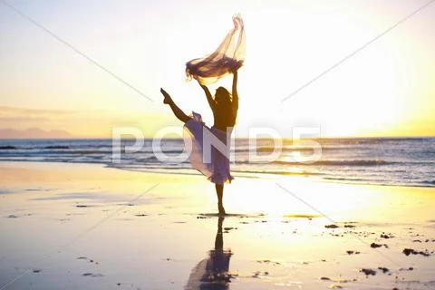 Young Woman Dancing On Sunlit Beach