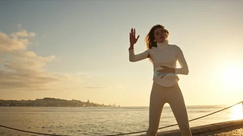 Young woman dancing at sunset by the river tagus in lisbon Stock Footage 309935874