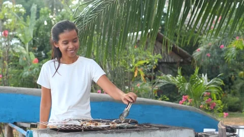 Young woman dancing while grilling fish in the garden. Stock Footage 138850224
