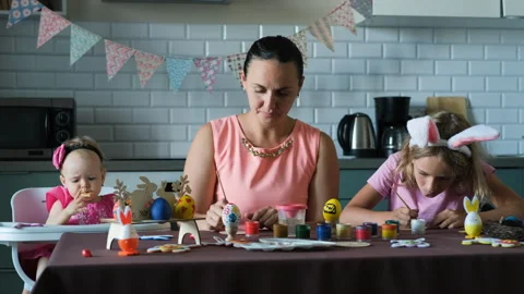 Young woman with daughters coloring Easter eggs Vídeos de archivo 263579880