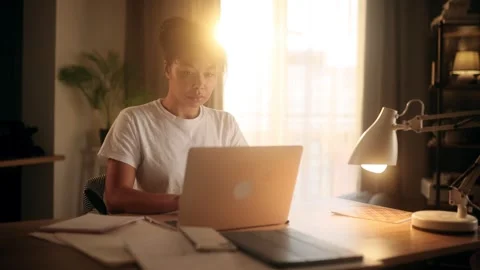 A young woman is deeply focused while working on her laptop in a bright home Stock Footage 303496127