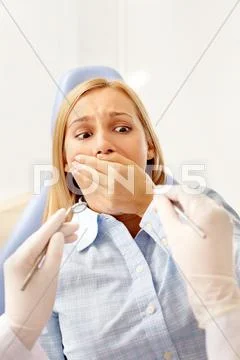 A young woman in dentist chair covering her mouth before dental tools Stock Photos
