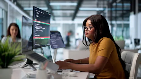 Young Woman Developer Compares Coding Changes On Laptop 库存影片 343890626