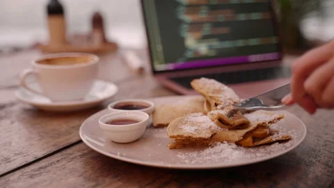 Young woman developer has lunch break eating food while working on laptop in Stock Footage 236709766