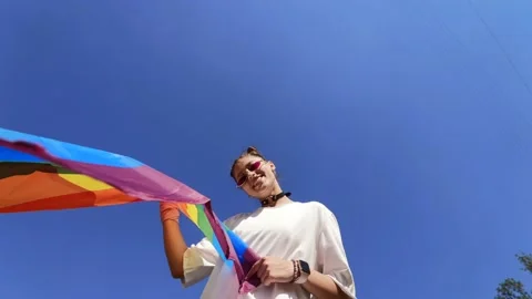 A young woman develops a rainbow flag against the sky Video stock 201331891