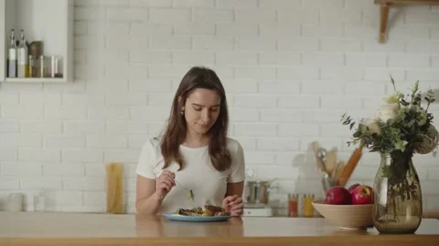 A young woman on a diet eats a vegetable salad. A brunette woman sits down at Stock Footage 235185744