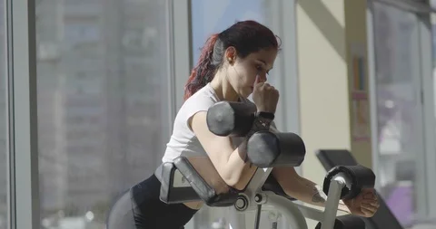 Young woman does exercise on biceps on training apparatus Stock Footage 116176341