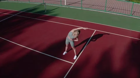 A young woman does flexibility exercises on a sports field on a sunny day. Stock Footage 329147376