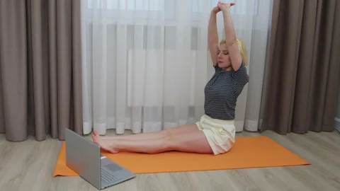 A young woman doing forward bending on a mat during online classes. Stock Footage 266415728