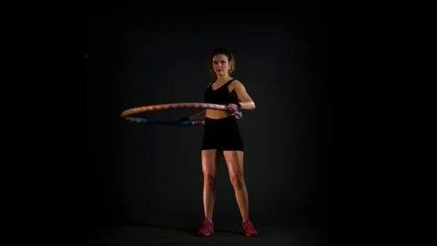 Young woman is doing a Hula-Hoop workout on black background Stock Footage
