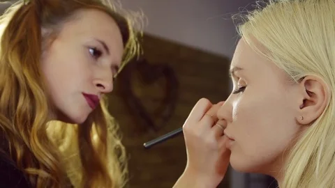 Young woman doing makeup on a model in a beauty salon. Stock Footage 71571293