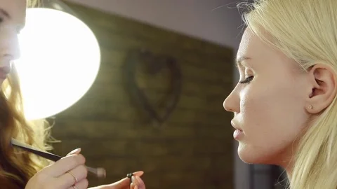 Young woman doing makeup on a model in a beauty salon. Stock Footage 71571335