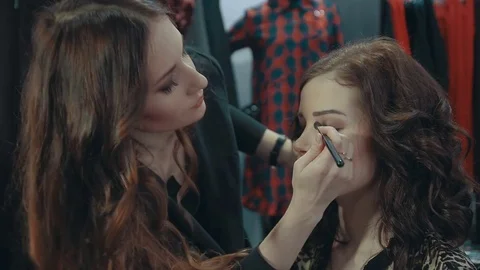 Young woman doing makeup on a model in the boutique of women's clothing. Stock Footage 74222202