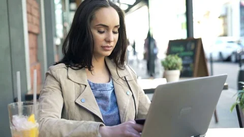 Young woman doing online shopping on laptop sitting in cafe in city Stock Footage