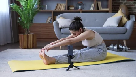 Young woman is doing physical exercises using a mobile app on her phone Stock Footage 310790978