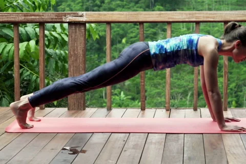 Young woman doing plank exercise on terrace with tropical view NTSC Stock Footage 55360044
