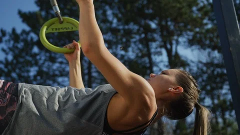 Young woman doing pull-ups with gymnastic rings Stock Footage 100031719