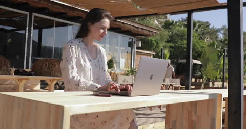 Young woman doing remote work with modern laptop while resting in bar near sea Stock-Footage 154335777
