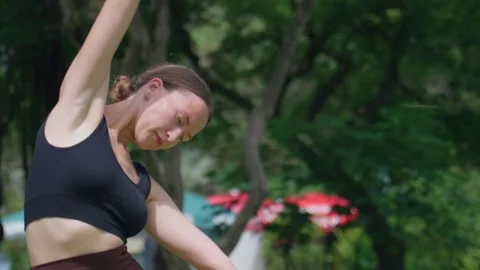 Young woman doing side bend exercise in park Stockbeeldmateriaal 284924406