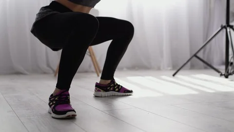 Young woman doing squats at home. A young girl engaged in fitness in the kitchen Stock Footage 104377341