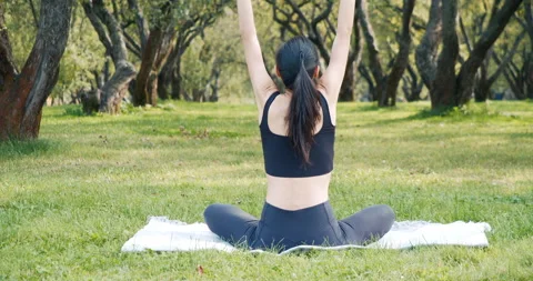 Young woman doing stretching while sitting on the grass in the park.Yoga concept Stock Footage 142068149