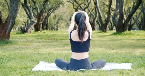 Young woman doing stretching while sitting on the grass in the park. Stock Footage 142495215