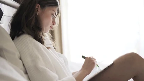 Young woman drawing on her tablet computer in bed, side view 動画素材 80432653
