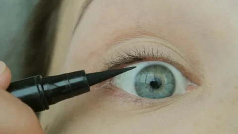 Young woman draws arrows using eyeliner. Eye natural makeup at home. Stock Footage 82335472
